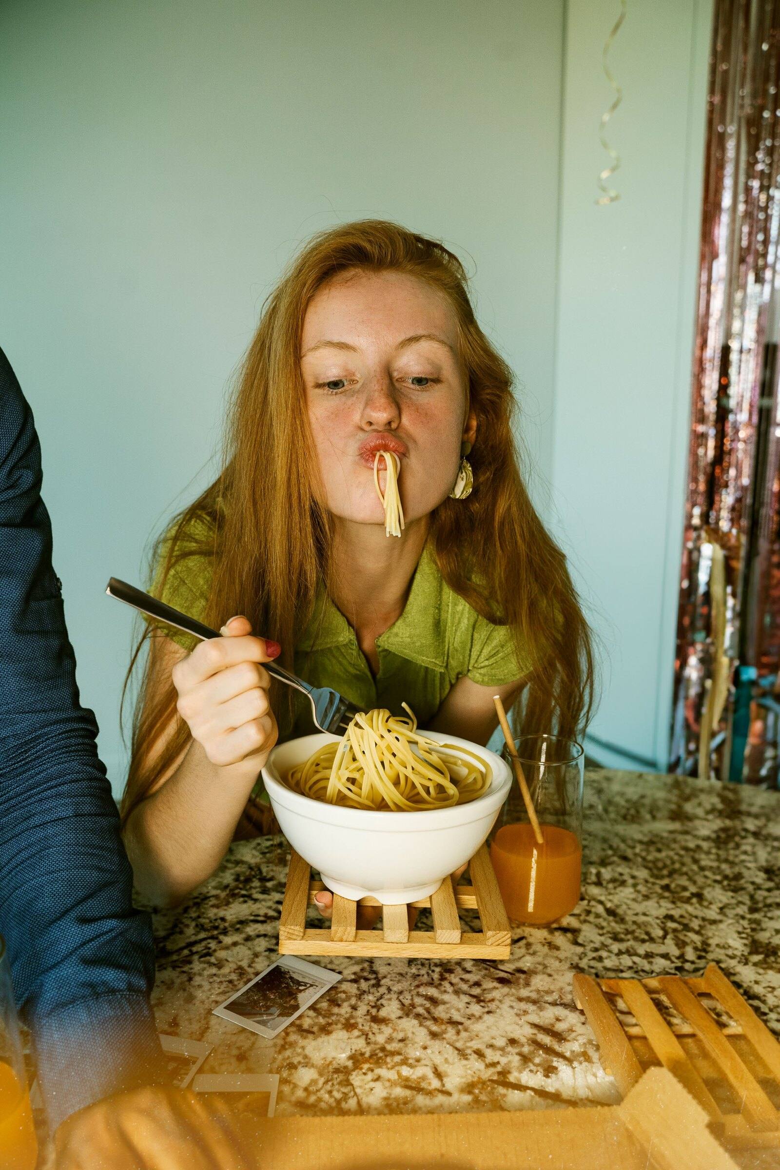 A guest slurping a strand of spaghetti from a bowl